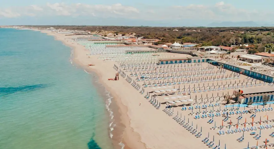 Widok z lotu ptaka na plażę w Marina di Cecina, Toskania, z rzędami leżaków i parasoli.
