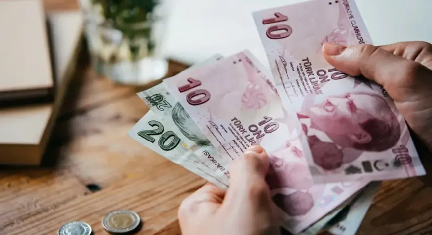 Ręka trzyma banknoty 10 i 20 lir tureckich. To pokazuje, czym płacić w Turcji.