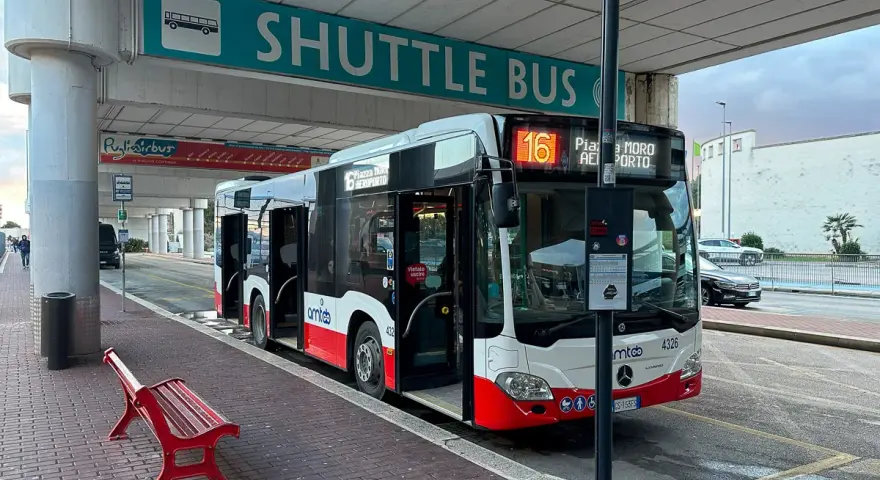 Autobus wahadłowy z lotniska do centrum miasta, z otwartymi drzwiami, gotowy do odjazdu.