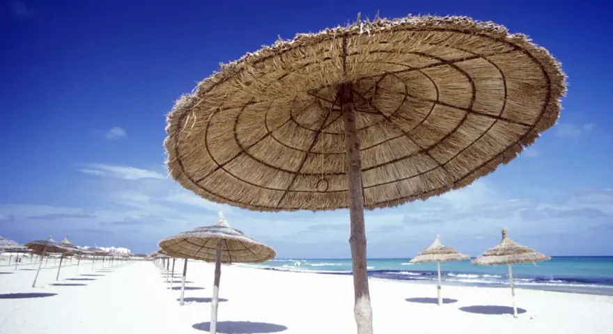 Słomiane parasole na pustej plaży w Tunezji. Marzec zapowiada piękną pogodę i spokojne morze.