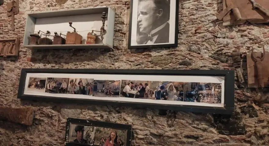 Pamiątki z miejsc, gdzie kręcono Ojca Chrzestnego: portret Marlona Brando, kolaż scen z filmu i stare młynki do kawy.