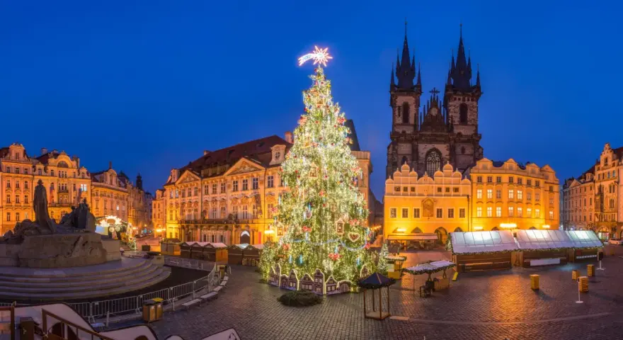 Jarmark bożonarodzeniowy w Pradze. Ogromna, oświetlona choinka na Rynku Staromiejskim, w tle gotycka architektura i zabytkowe kamienice.