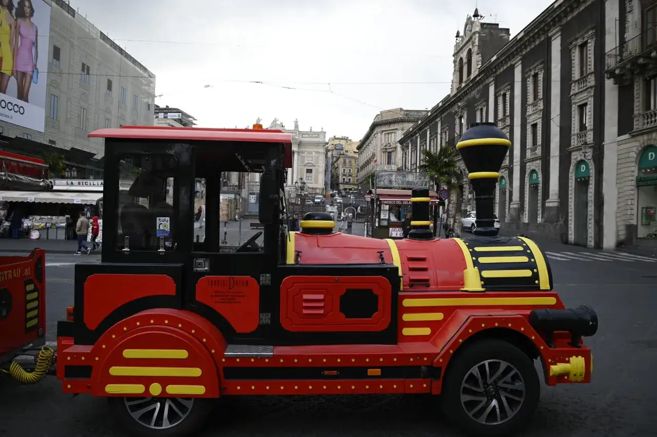 Czerwony pociąg turystyczny na ulicy Sycylii. Ceny na Sycylii mogą być różne, ale ta przejażdżka to świetna zabawa.