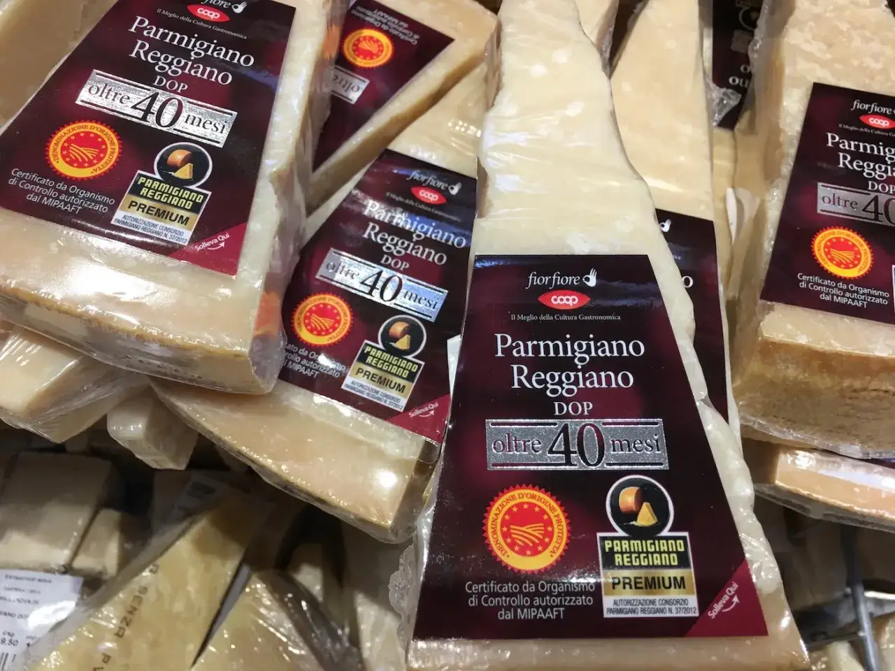 Kawałki Parmigiano Reggiano, znanego jako parmezan, w opakowaniach z etykietami 
