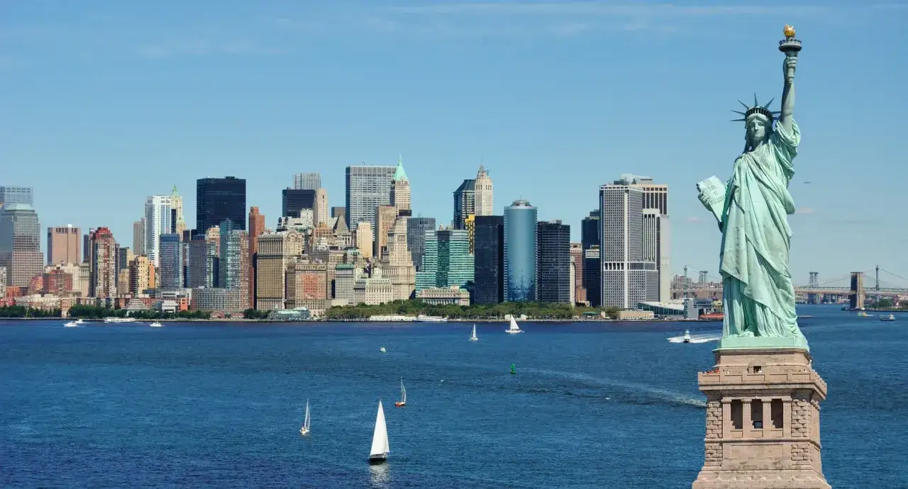 Statua Wolności i panorama Manhattanu, klasyczne nowy jork atrakcje. W tle żaglówki i mosty.