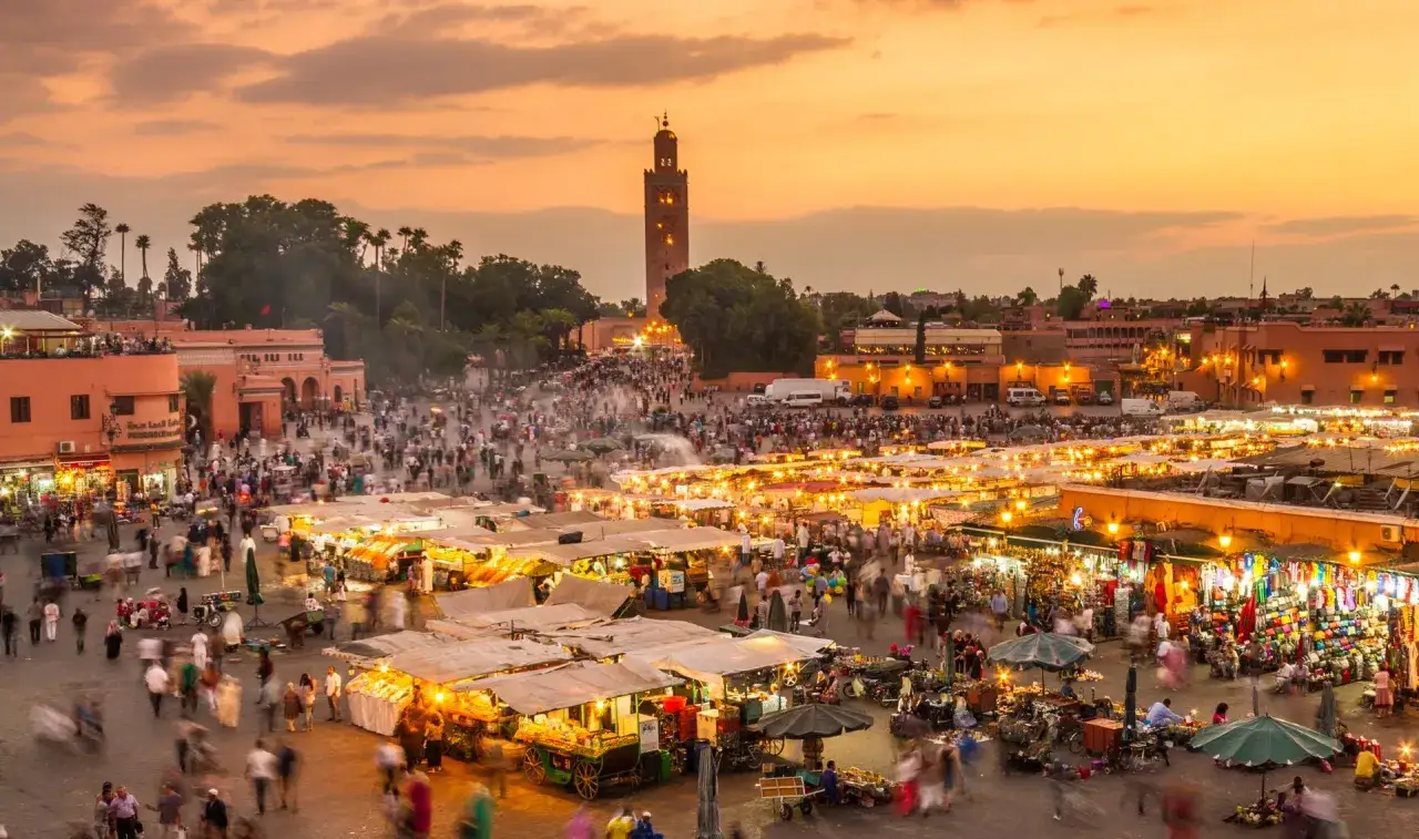 Tętniący życiem plac Dżamaa al-Fina w Marrakeszu nocą. Mnóstwo straganów, ludzi i wieża Koutoubia w tle. To obowiązkowy punkt, jeśli zastanawiasz się, co zobaczyć w Marrakeszu.