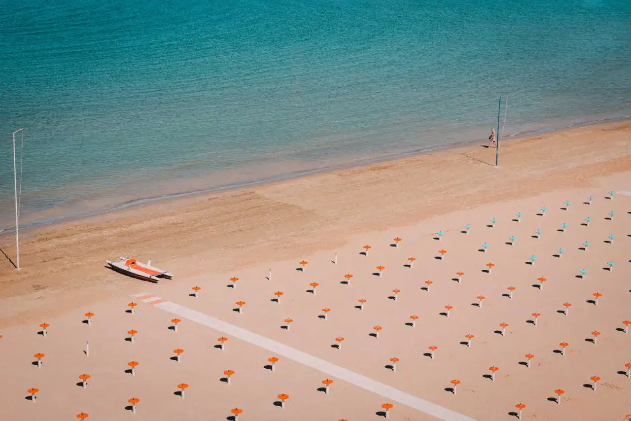 Plaża w Rimini, czy warto? Widok z g&oacute;ry na puste leżaki, ł&oacute;dź i turkusowe morze. Idealne miejsce na wakacje.